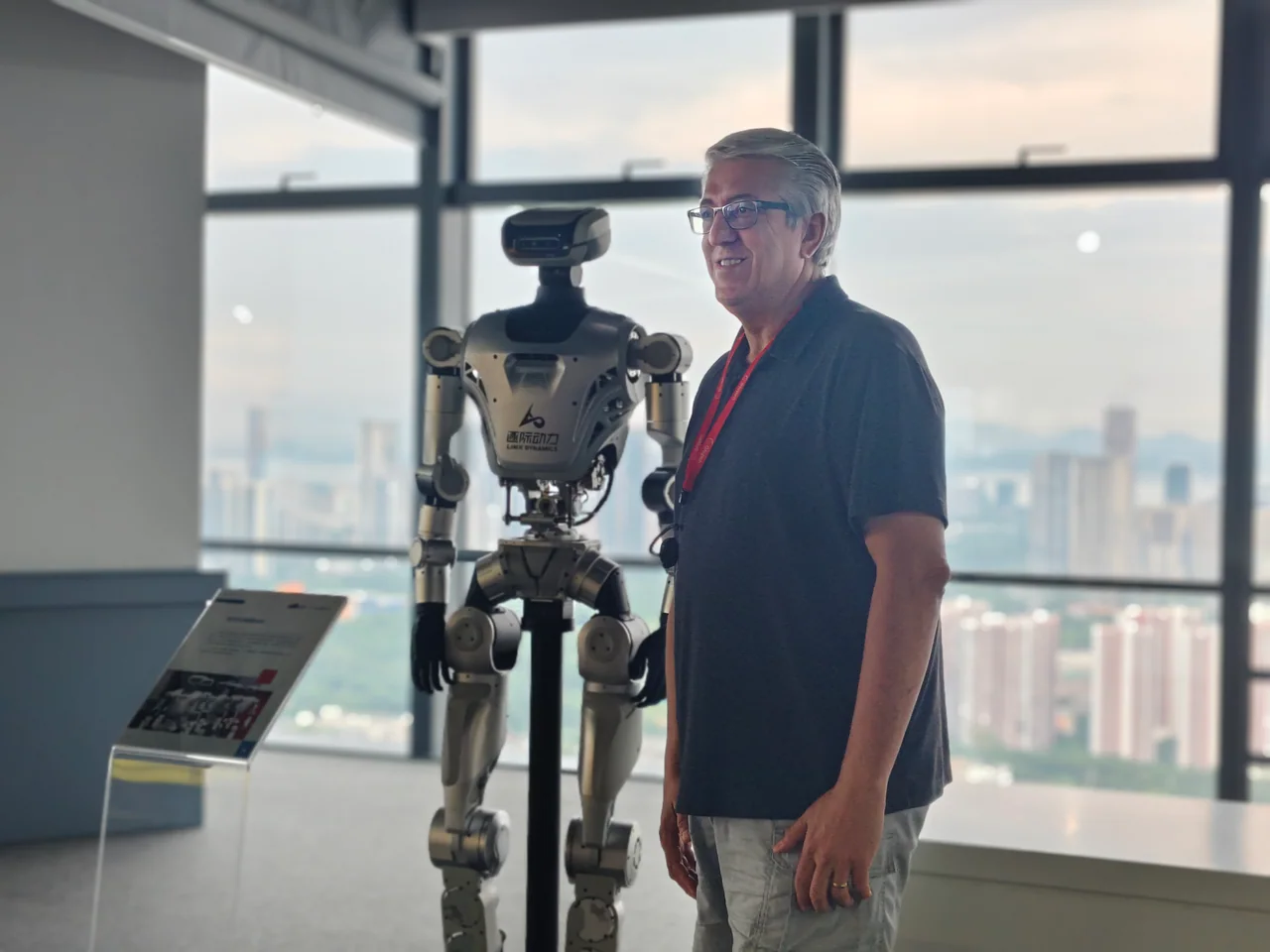 A visitor standing next to a full-size LimX humanoid robot.