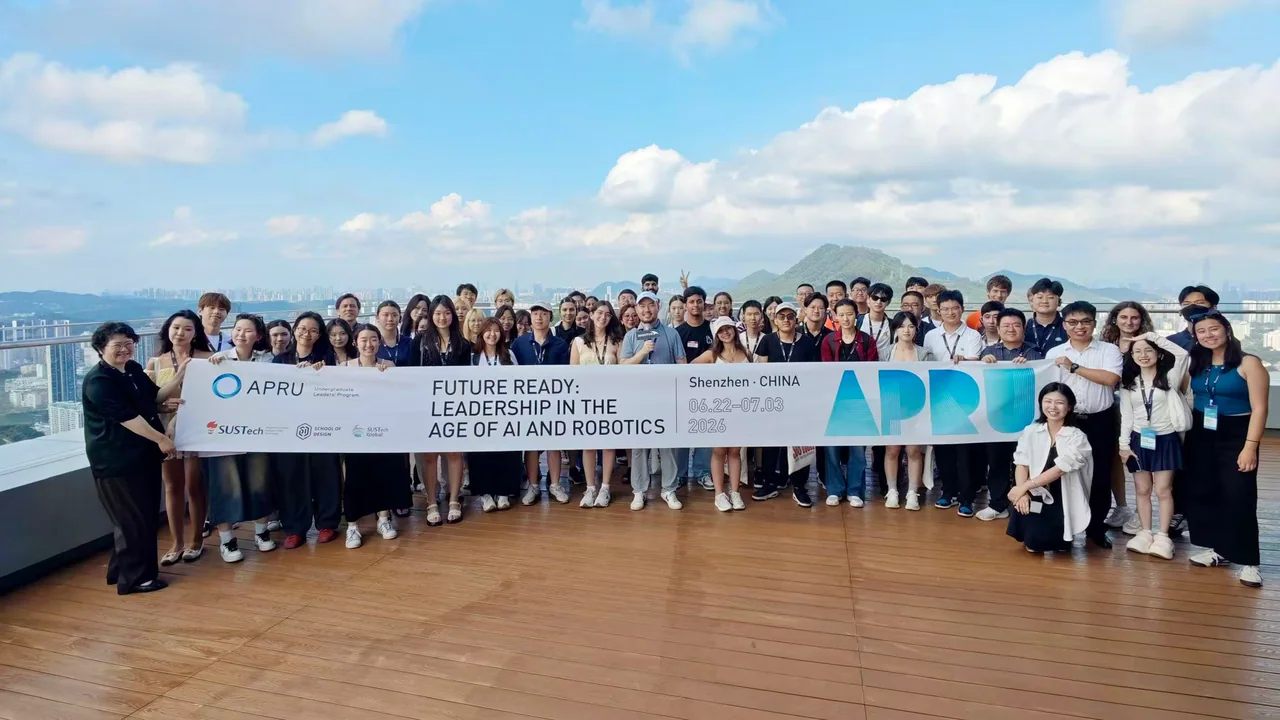 An international university group gathers on the timber sky deck with the Shenzhen skyline behind them.